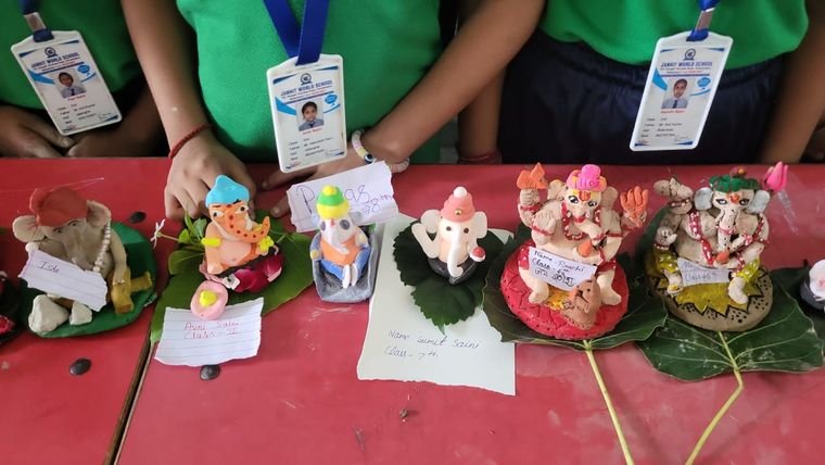 Close view of student-made clay Ganesh idols with name cards, Janhit World School