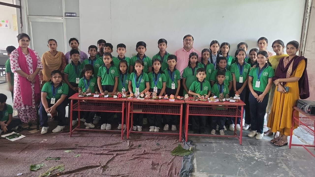 Students and teachers beside a display of handmade craft work at Janhit World School