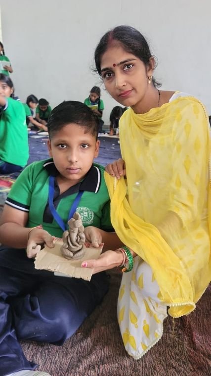 A student with his clay model and his teacher at Janhit World School