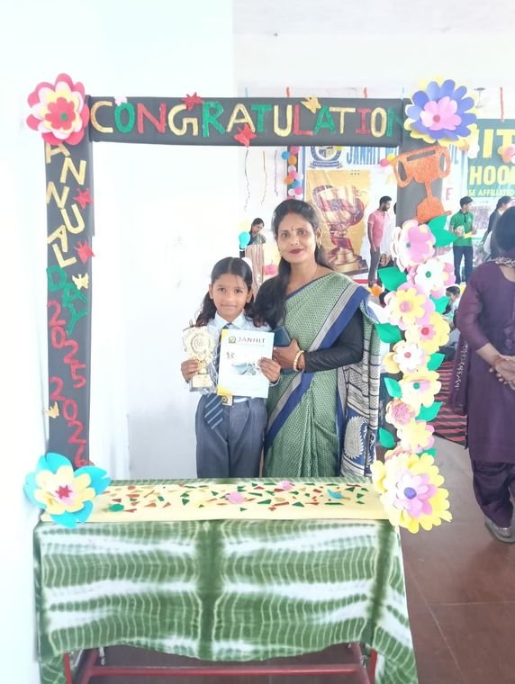 A student with her teacher holding an award certificate at Janhit World School