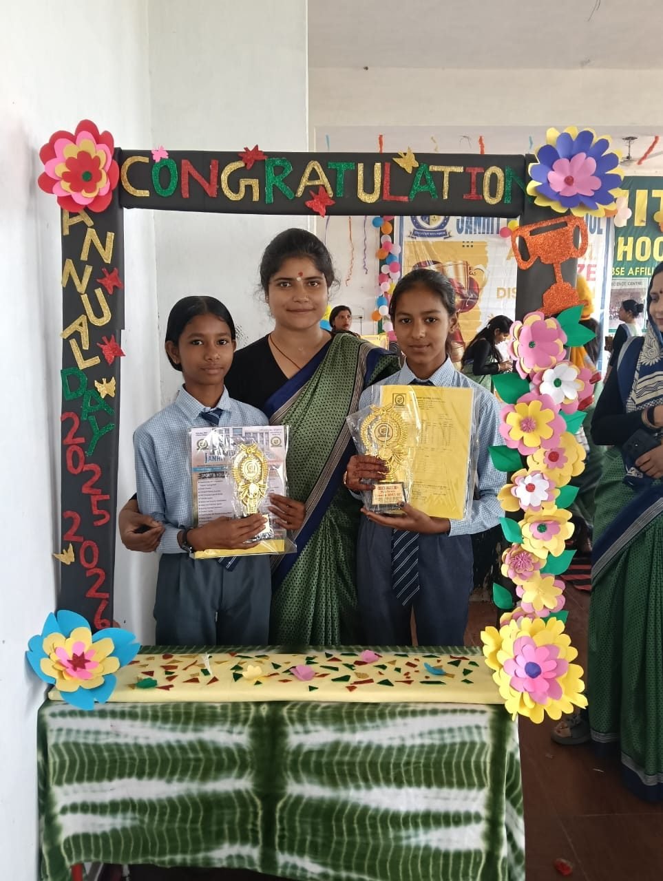Two students of Janhit World School holding trophies with their teacher